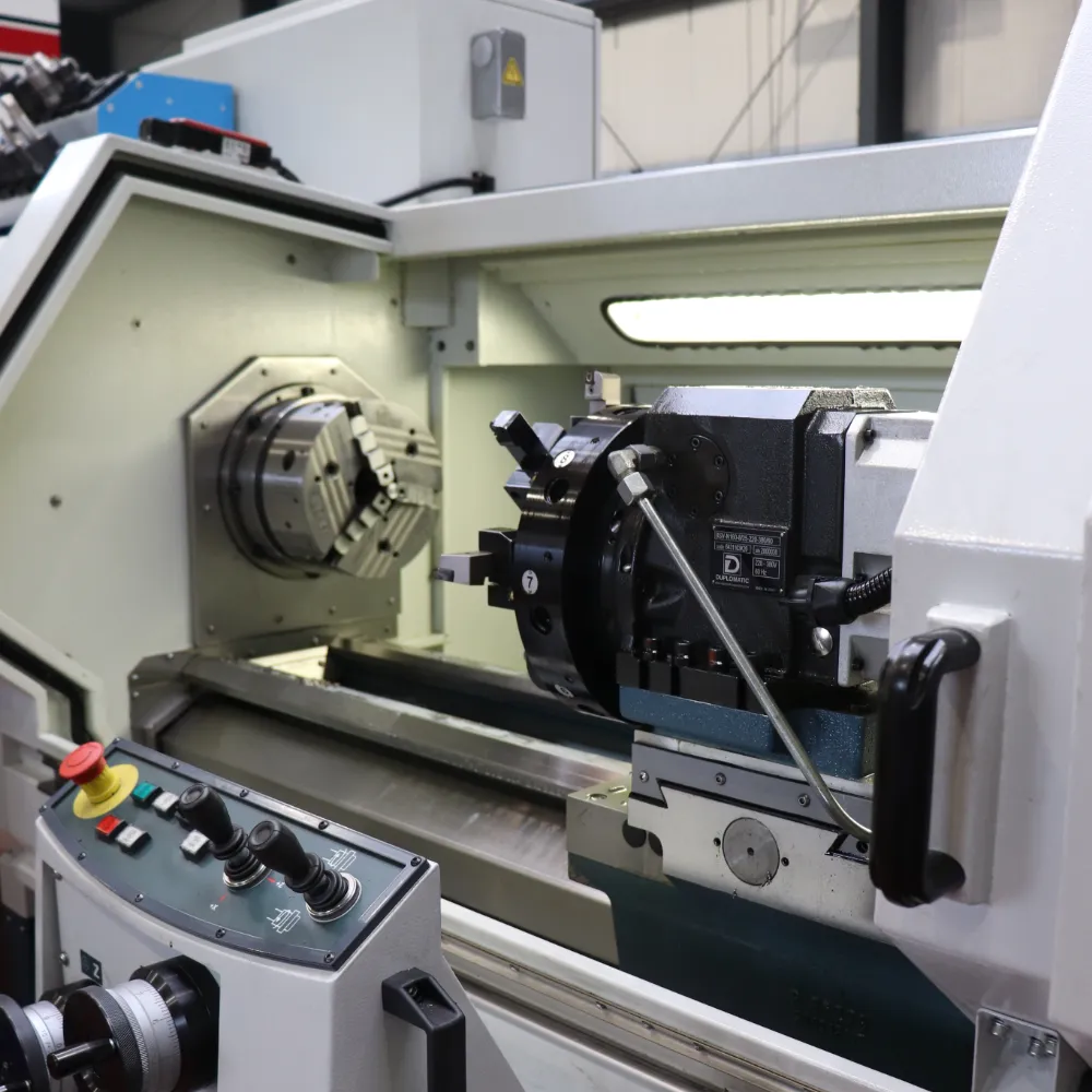 Mitarbeiter erklärt einem Kollegen die Bedienung einer CNC-Drehmaschine am Steuerungspanel