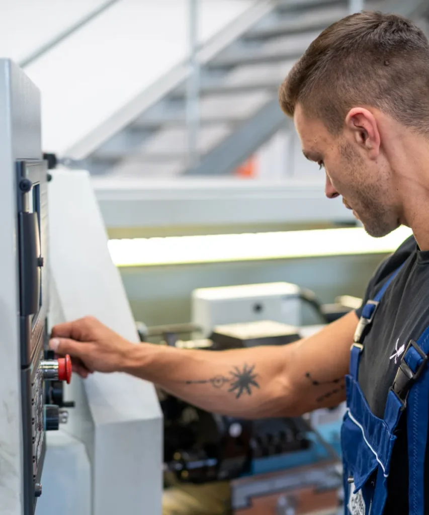 Mitarbeiter bedient das Steuerpult einer CNC-Maschine